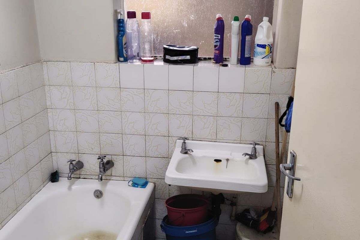 A dated bathroom featuring a standard bathtub and wall-mounted basin with tiled splashbacks, requiring cosmetic updates and maintenance to improve its overall condition.