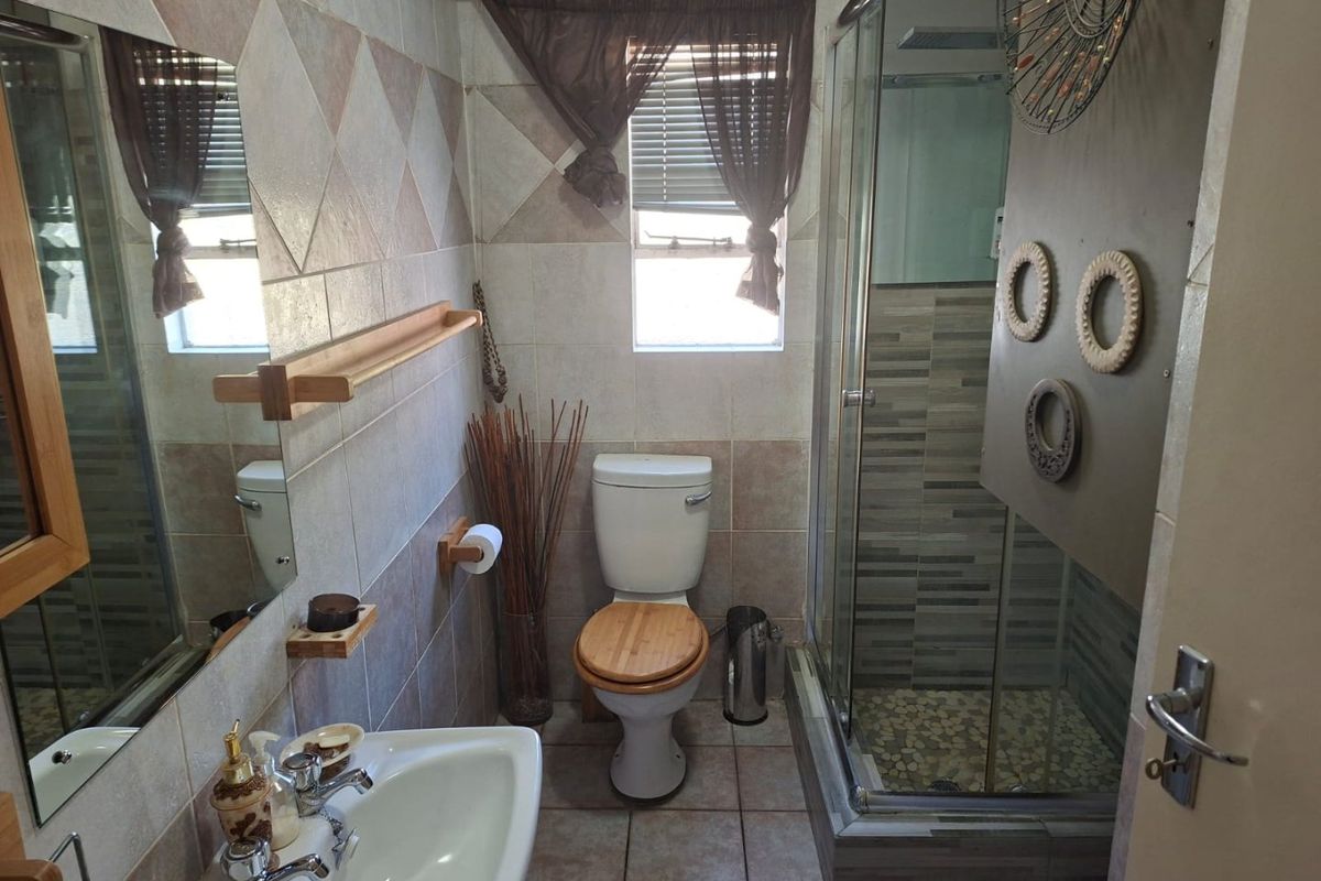 A functional bathroom featuring a shower enclosure, pedestal basin, toilet, and tiled finishes throughout.