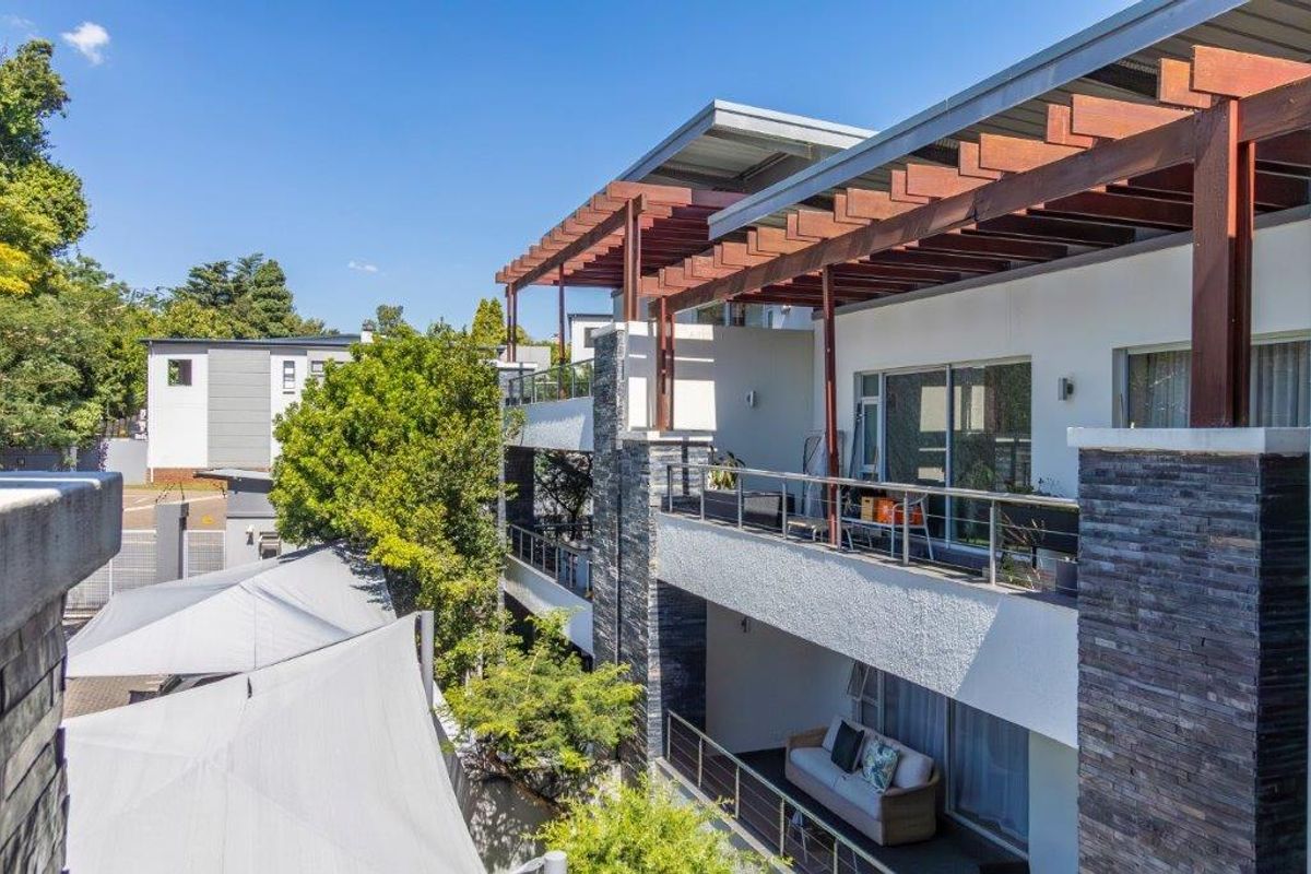A view of the apartment building exterior featuring multi-level balconies with timber pergolas and stone-clad pillars.
