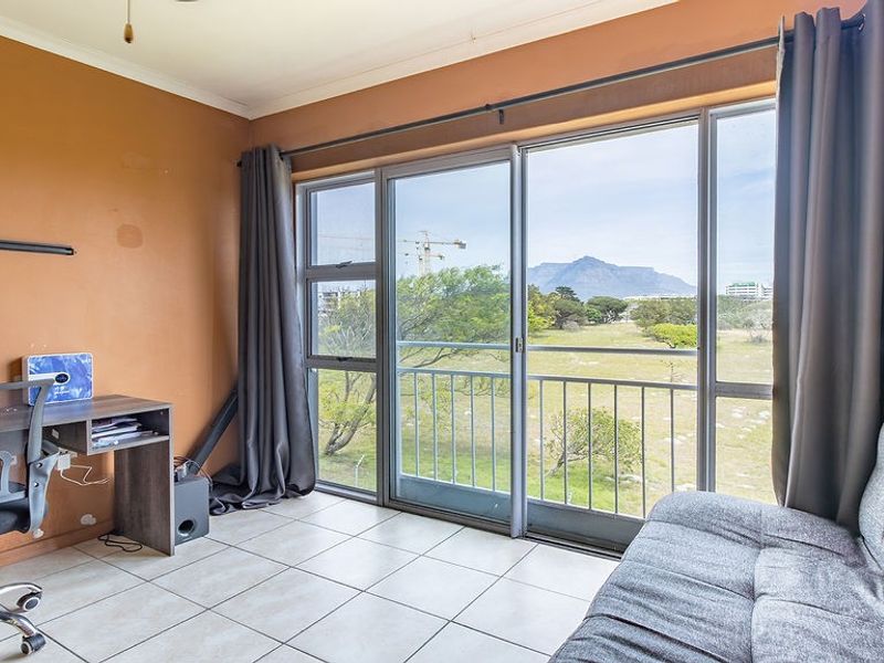 A living area featuring tiled flooring and large sliding glass doors that open to a balcony with scenic mountain views.