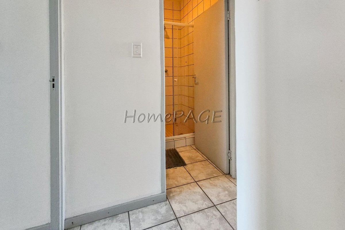 A view from a hallway looking into a small bathroom featuring tiled flooring and a shower enclosure.