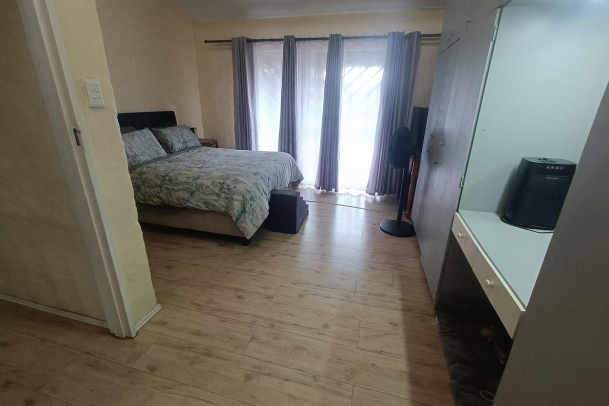 A bedroom featuring light wood-look laminate flooring, built-in cabinetry with a vanity area, and sliding glass doors leading to an outdoor space.