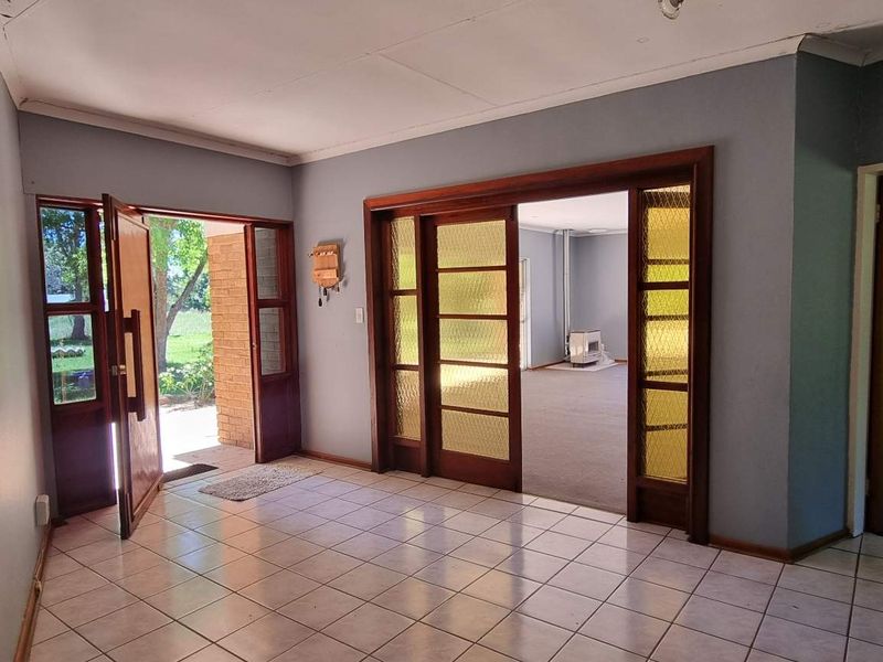 Spacious entrance hall featuring tiled flooring, timber-framed glass sliding doors leading to the living area, and direct access to the front exterior.