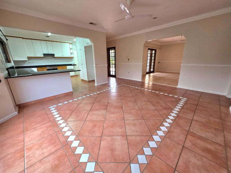 Spacious open-plan living and kitchen area featuring ceramic tile flooring, built-in cabinetry with granite countertops, and classic architectural molding details.