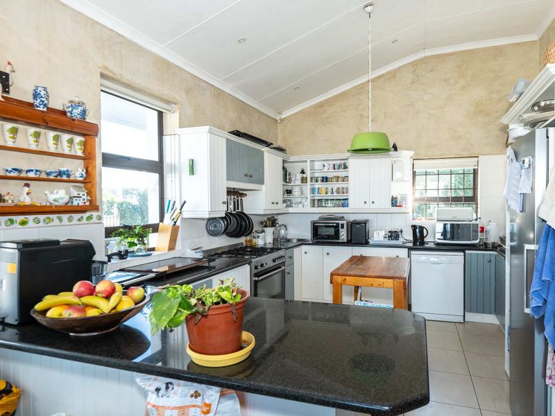 A functional kitchen featuring granite countertops, built-in cabinetry, a gas hob, and a vaulted ceiling, providing a practical workspace with ample storage.
