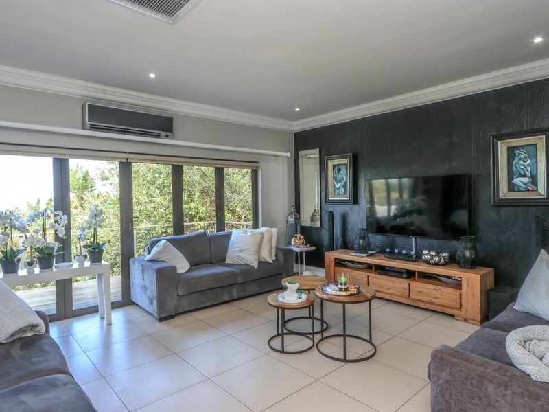 A well-maintained living room featuring tiled floors, a textured feature wall, recessed lighting, and large sliding glass doors providing natural light and outdoor access.