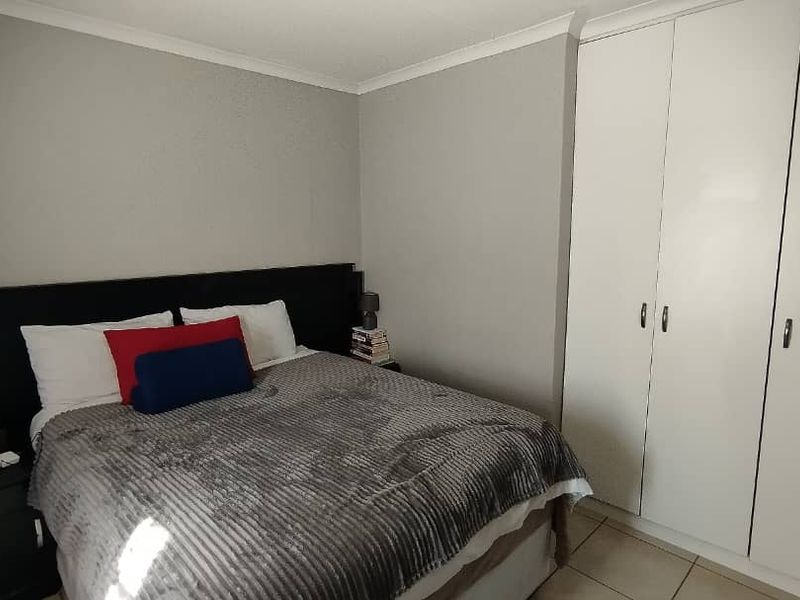 A well-maintained bedroom featuring neutral wall tones, tiled flooring, and ample built-in cupboard storage.