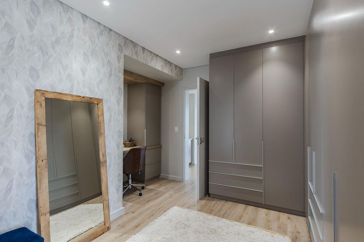 A well-appointed bedroom featuring modern built-in cabinetry, recessed ceiling lighting, and light wood-look flooring, creating a clean and contemporary living space.