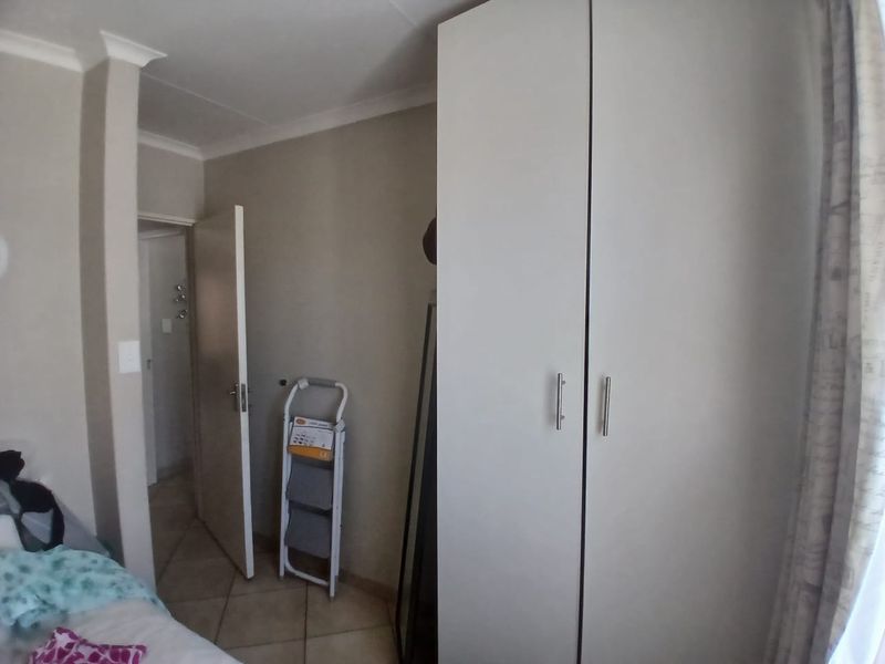 A bedroom featuring a built-in wardrobe, tiled flooring, and coved ceiling details.