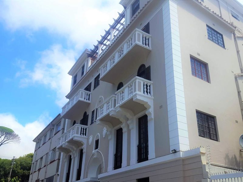 A low-angle view of a multi-story apartment building facade featuring classic architectural detailing, white balustrades, and multiple balconies.