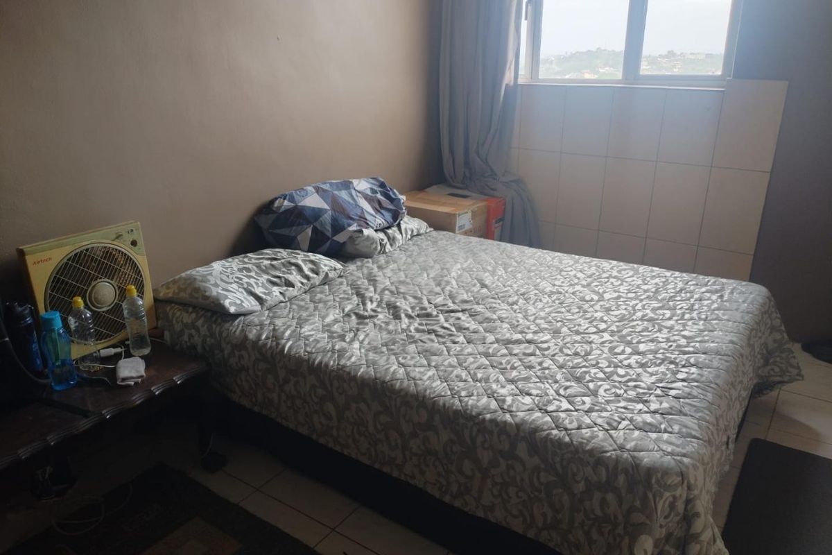 A bedroom featuring tiled flooring and an aluminium window frame, requiring cosmetic updates to improve the overall aesthetic and condition of the space.