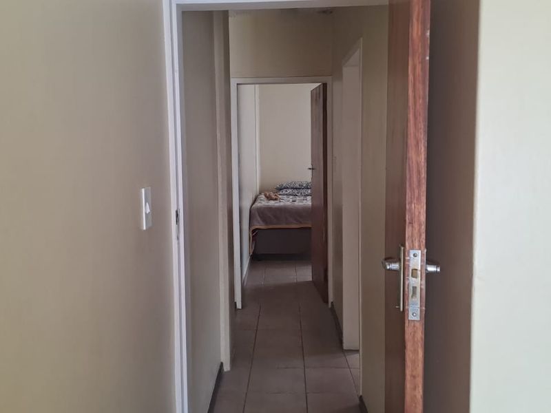 A functional hallway connecting interior rooms, featuring tiled flooring and standard internal door fixtures.