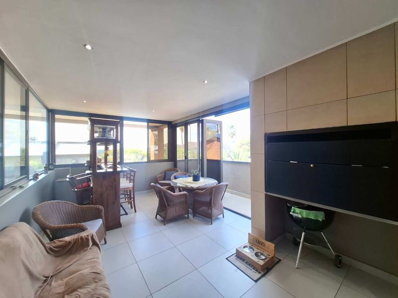 Enclosed patio area featuring a built-in braai, tiled flooring, and large sliding glass doors providing ample natural light and outdoor access.