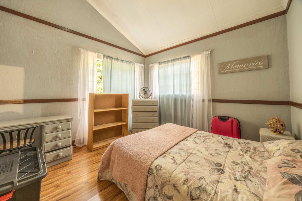A bedroom featuring laminate flooring, a vaulted ceiling, and chair rail molding, providing a functional space with natural light.