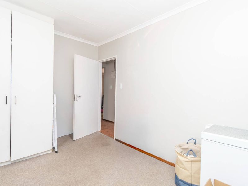 A clean, neutral bedroom featuring built-in cupboards and carpeted flooring, offering a blank canvas for personalization.