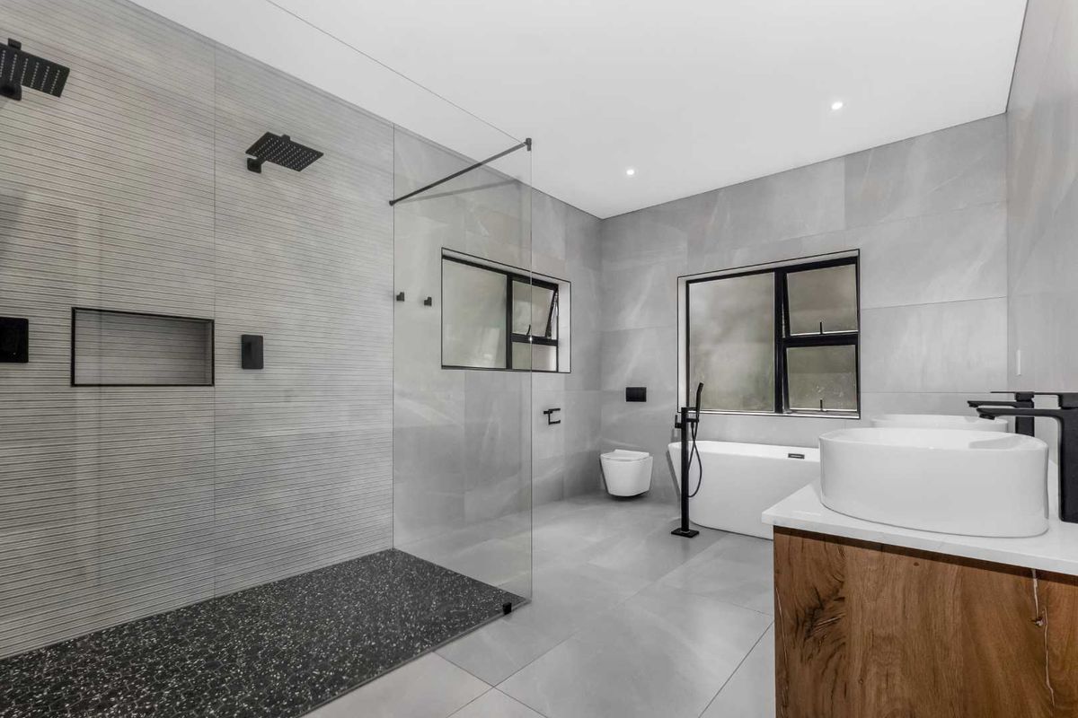 Modern bathroom featuring a large walk-in shower with rainfall showerhead, freestanding bathtub, and a contemporary vanity with vessel sink.