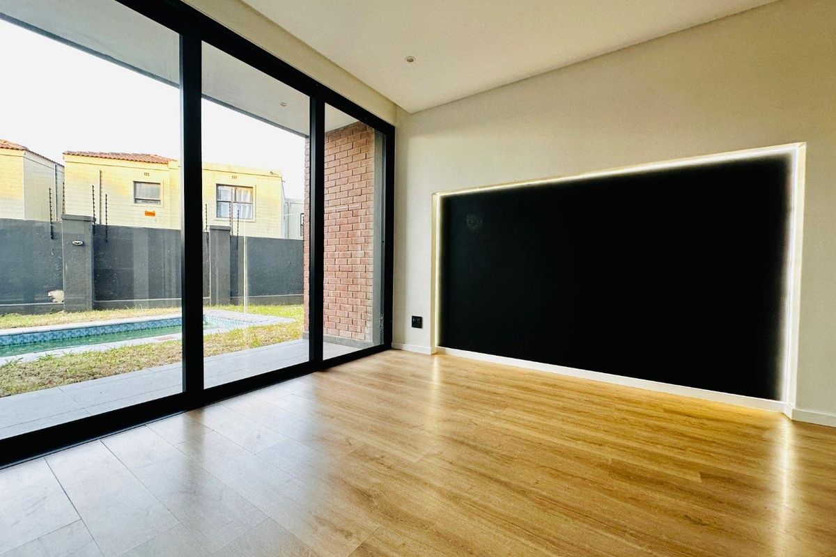 Modern living area featuring large sliding glass doors, laminate wood flooring, and a striking feature wall with integrated recessed LED lighting.