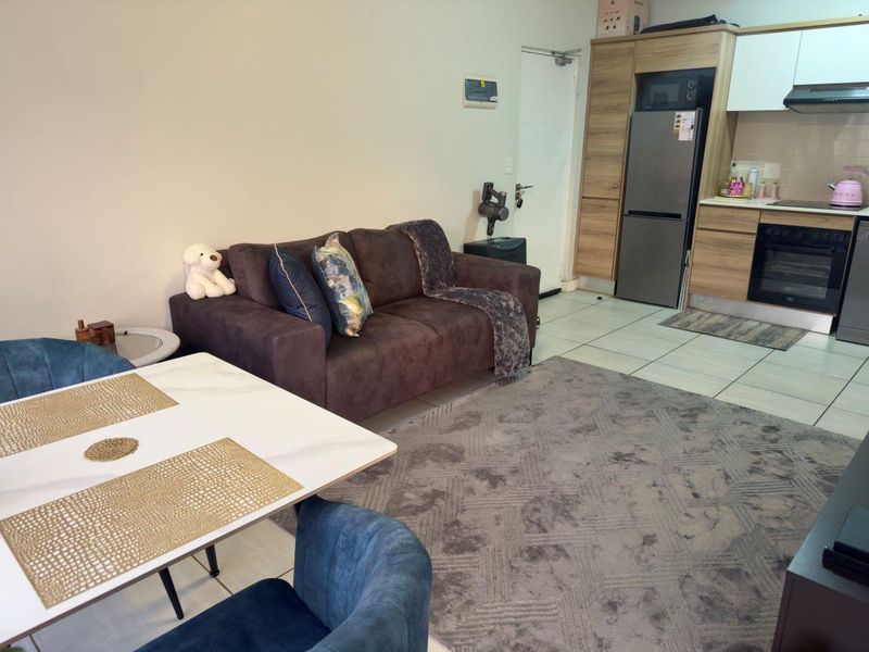 Open-plan living and kitchen area featuring modern built-in cabinetry, integrated appliances, and tiled flooring in a well-maintained apartment setting.