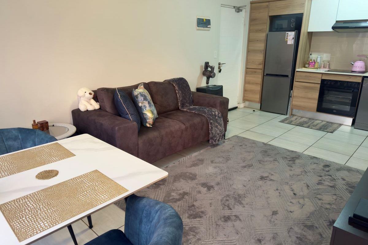 Open-plan living and kitchen area featuring modern built-in cabinetry, integrated appliances, and tiled flooring in a well-maintained apartment setting.