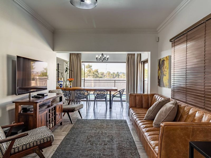 Spacious open-plan living and dining area featuring tiled floors, crown molding, and large sliding doors that open to an outdoor patio space.