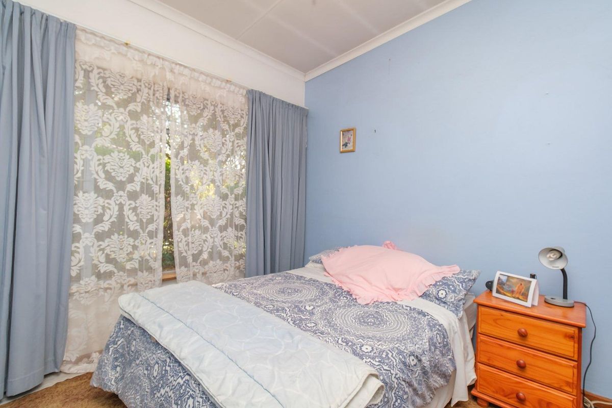 A standard bedroom featuring blue painted walls, coving, and a window with curtains.