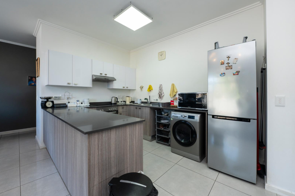 A functional kitchen featuring modern cabinetry, stone countertops, integrated appliances, and tiled flooring, offering a clean and practical workspace.