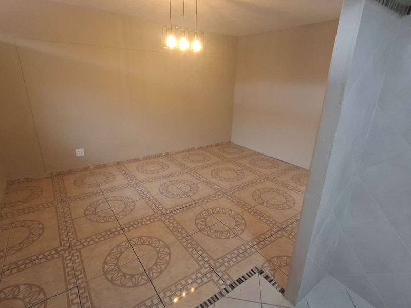 An empty living area featuring patterned ceramic floor tiles and modern pendant lighting, providing a neutral blank canvas for interior design.