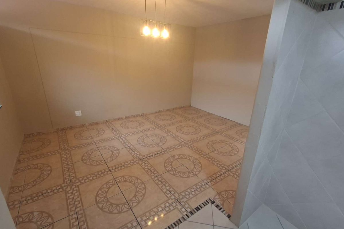 An empty living area featuring patterned ceramic floor tiles and modern pendant lighting, providing a neutral blank canvas for interior design.