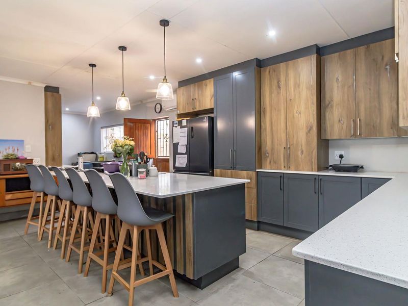 Modern kitchen featuring a large island with quartz countertops, two-tone cabinetry, and stylish pendant lighting, creating a functional and contemporary culinary space.