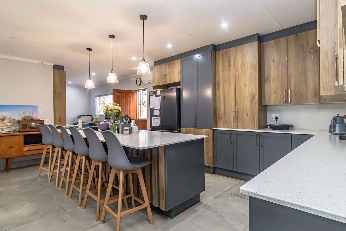 Modern kitchen featuring a large island with quartz countertops, two-tone cabinetry, and stylish pendant lighting, creating a functional and contemporary culinary space.