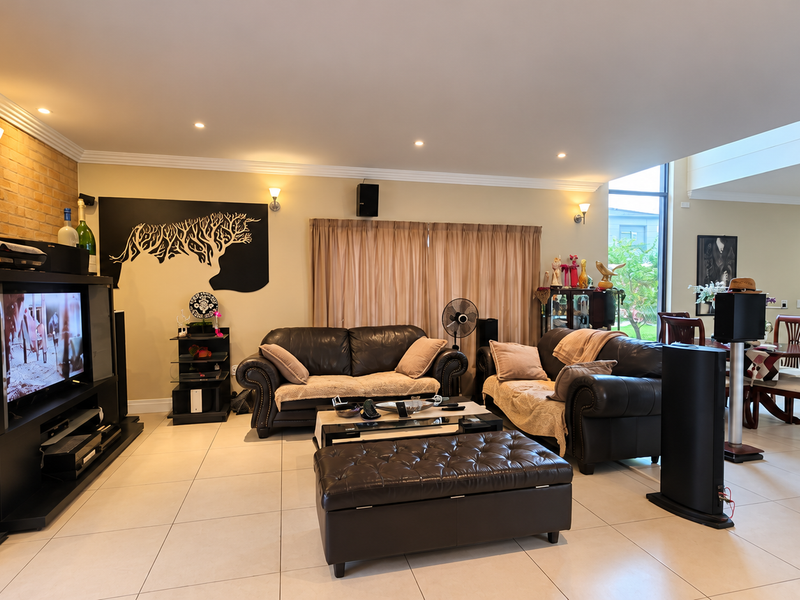 Spacious open-plan living and dining area featuring tiled floors, an exposed brick feature wall, and a modern skylight providing ample natural light.