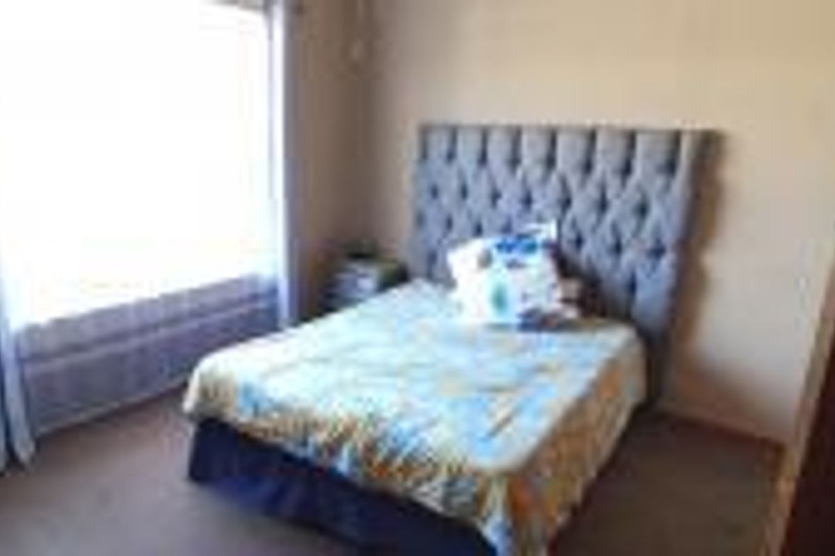 A standard bedroom featuring a large window that provides natural light to the space.