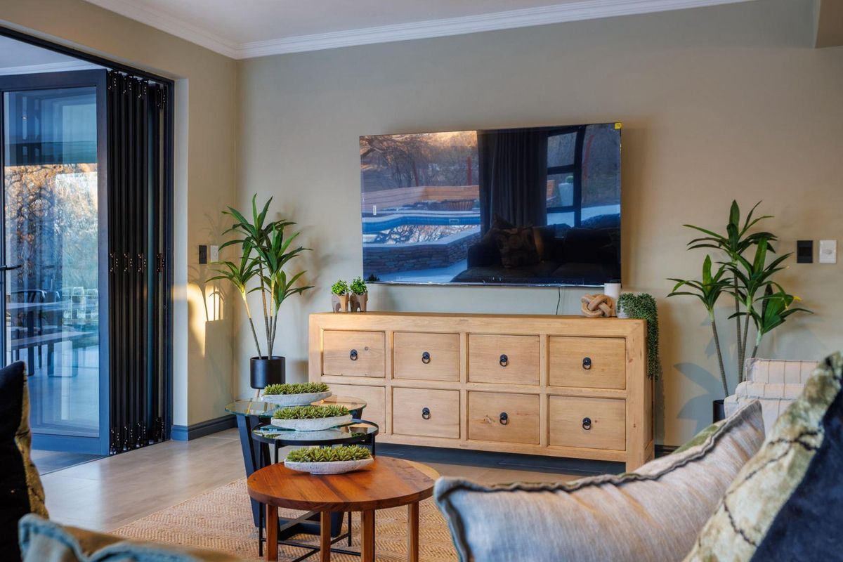 A well-appointed living room featuring modern bi-fold doors that open to the exterior, crown molding, and high-quality laminate flooring.