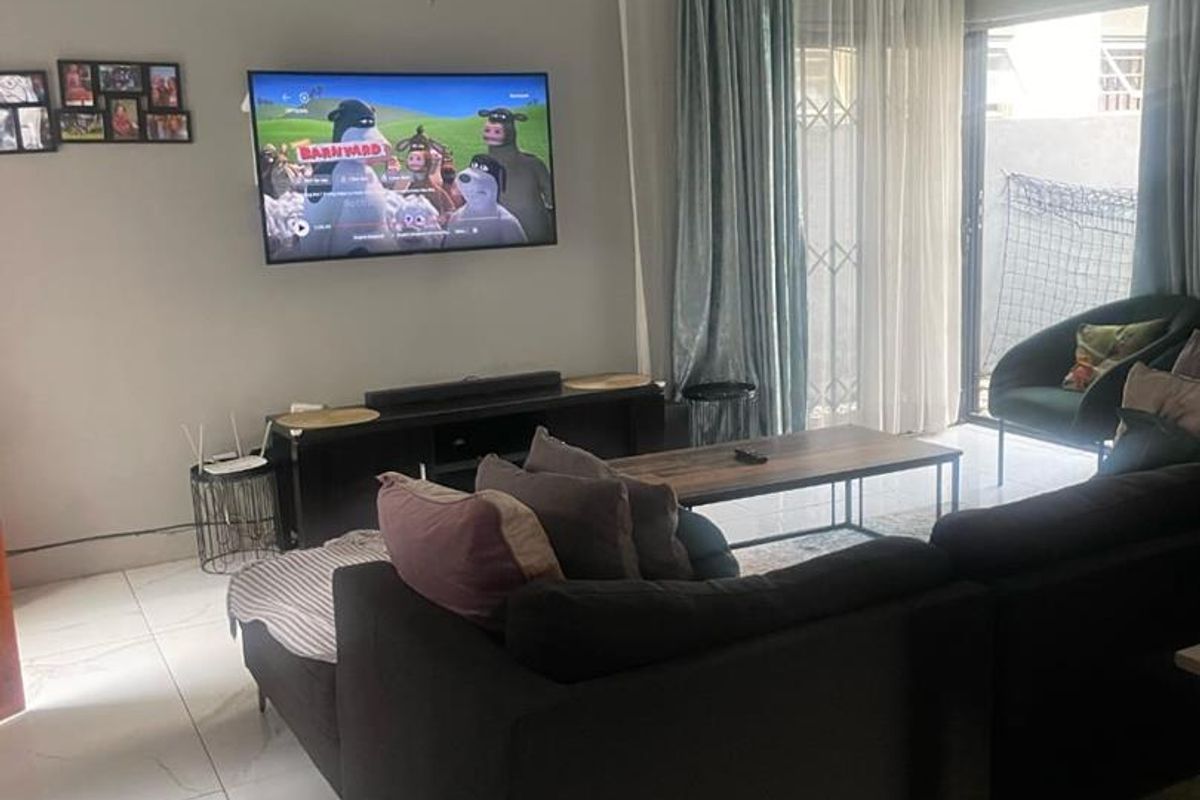 A comfortable living room featuring large format floor tiles, neutral wall tones, and sliding glass doors providing access to the outdoor area.
