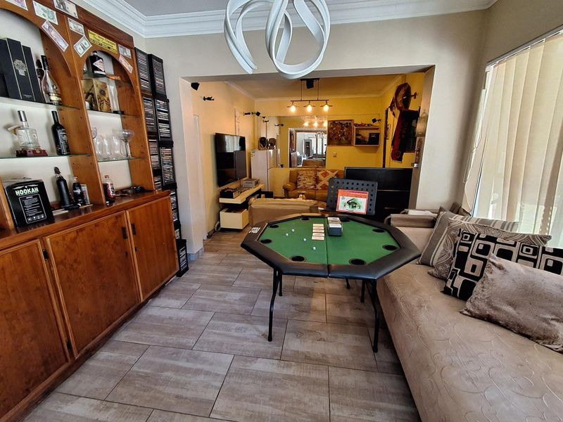 A living room featuring tiled flooring, built-in wooden cabinetry, and cove ceiling molding, offering a functional space with an open-plan layout.