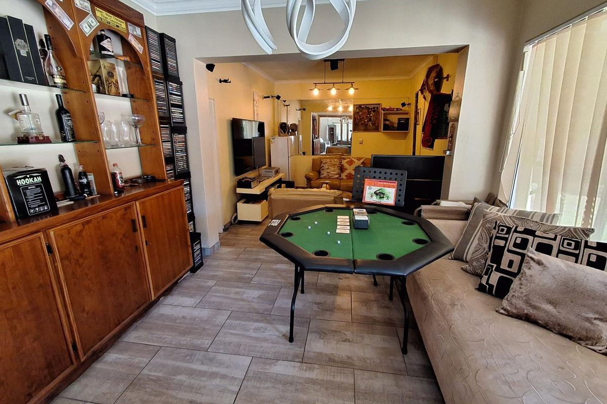 A living room featuring tiled flooring, built-in wooden cabinetry, and cove ceiling molding, offering a functional space with an open-plan layout.