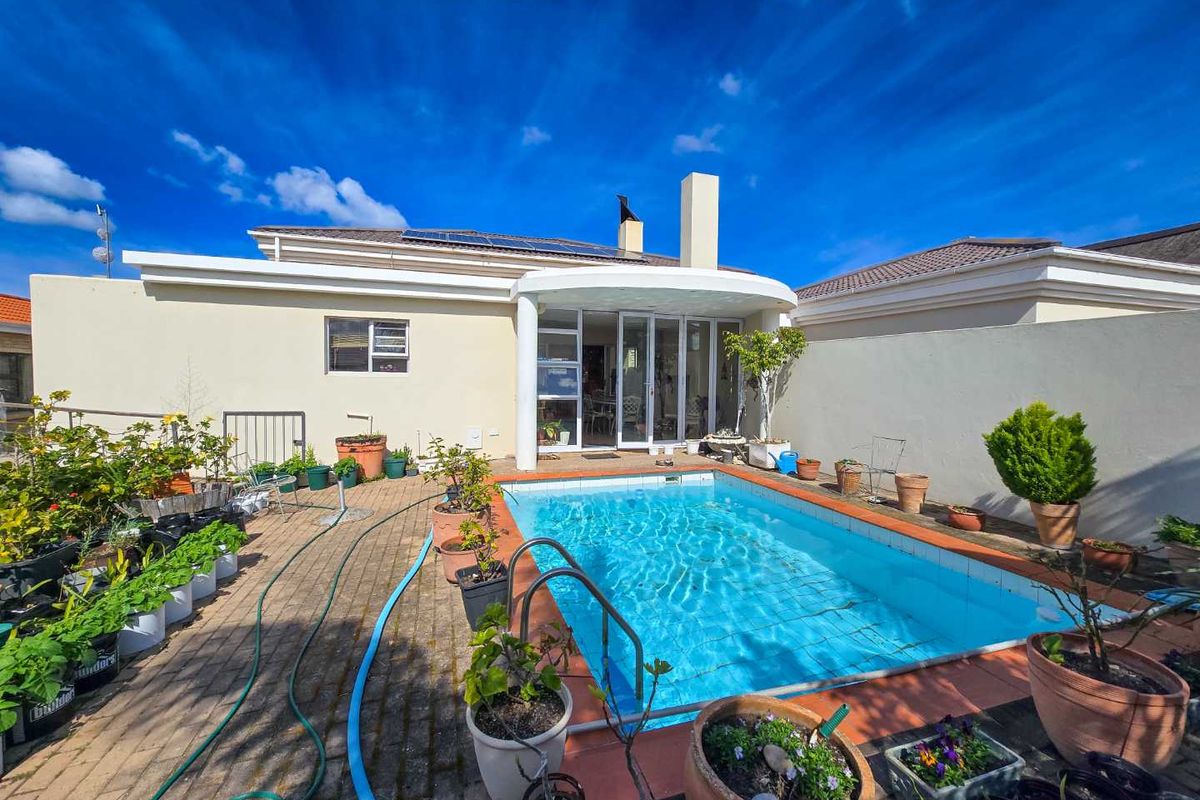 Rear exterior view featuring a swimming pool, paved patio area, and direct access to the home through sliding glass doors.