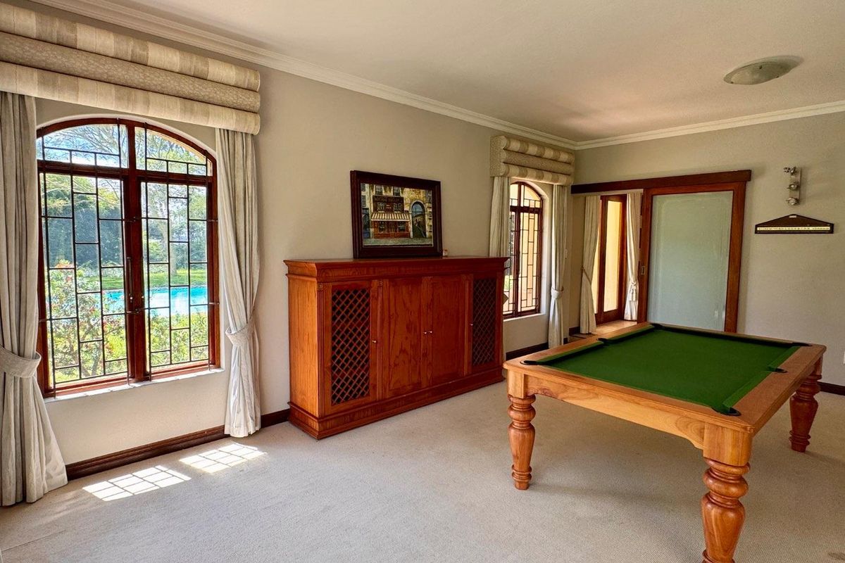 Spacious living area featuring arched timber-framed windows, neutral carpeting, and elegant crown molding, offering a bright and inviting atmosphere.