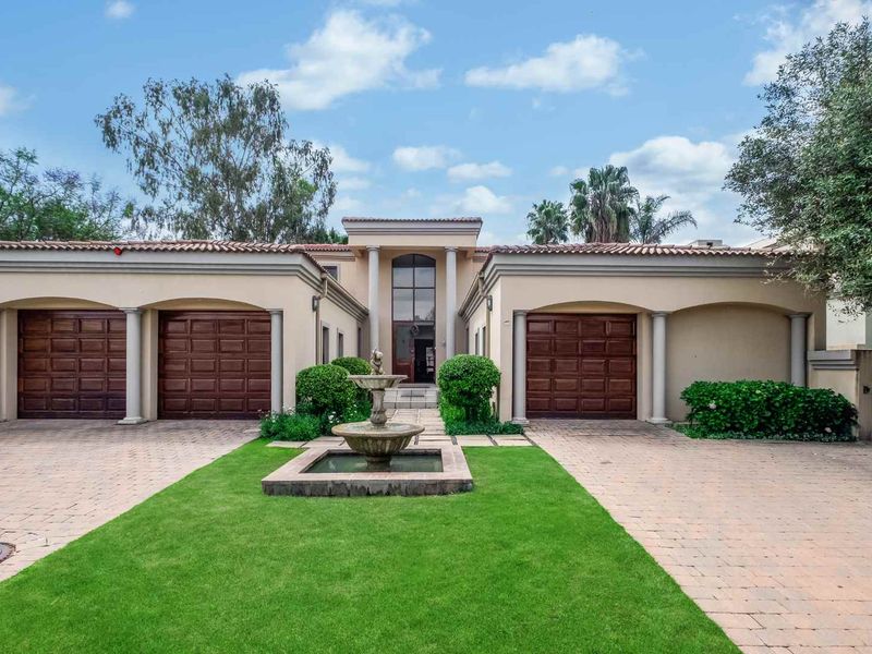 A grand front elevation featuring a triple garage, paved driveway, central water fountain, and elegant architectural columns leading to the main entrance.