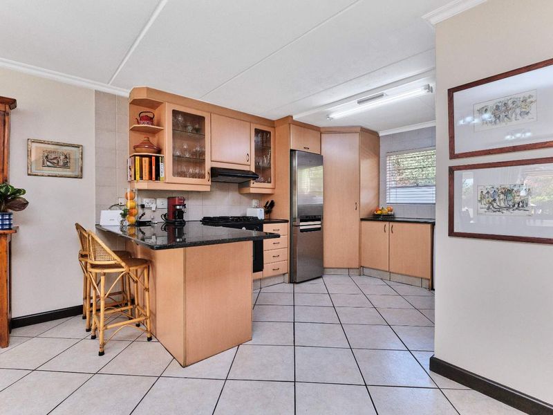 A functional kitchen featuring light wood cabinetry, granite countertops, a breakfast nook, and tiled flooring, offering a practical layout for daily use.