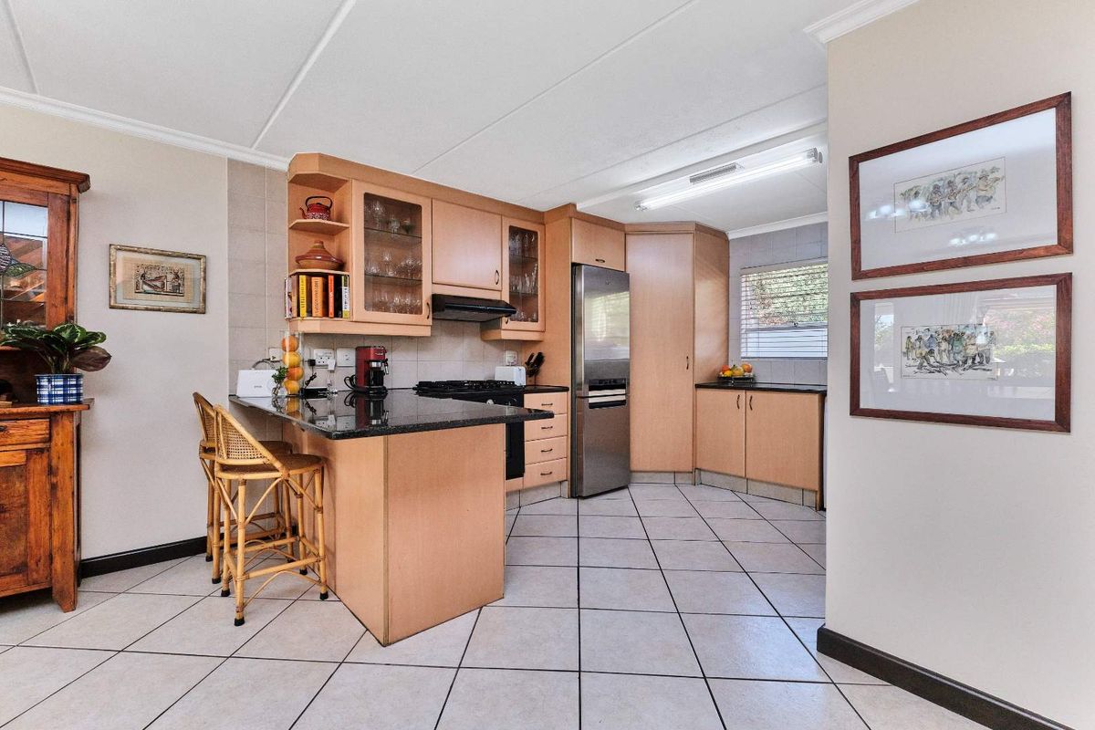 A functional kitchen featuring light wood cabinetry, granite countertops, a breakfast nook, and tiled flooring, offering a practical layout for daily use.