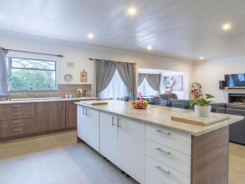 Spacious open-plan living area featuring a modern kitchen with a central island, integrated cabinetry, and a cozy fireplace, perfect for family living and entertaining.