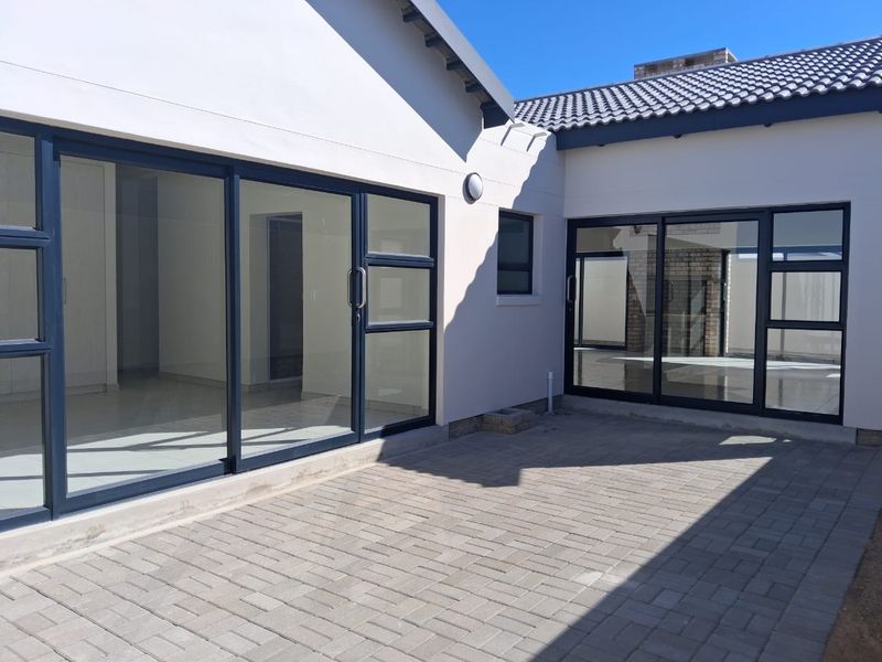 A clean, modern rear patio area featuring paved flooring and large sliding glass doors providing seamless access to the interior living spaces.
