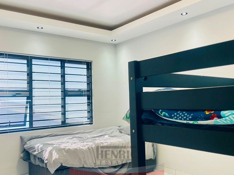 A well-lit bedroom featuring a modern bulkhead ceiling with recessed lighting and large aluminium-framed windows.