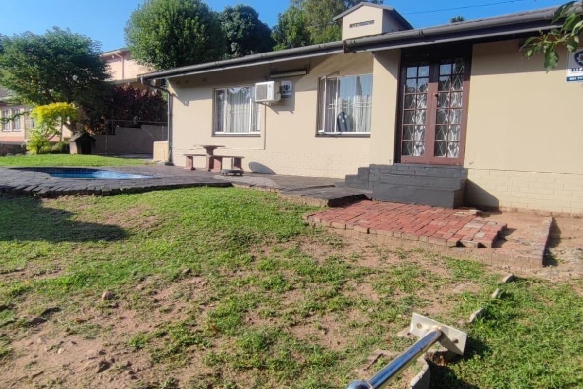 Rear exterior view of the house featuring a swimming pool, paved patio area, and direct access through a security door.