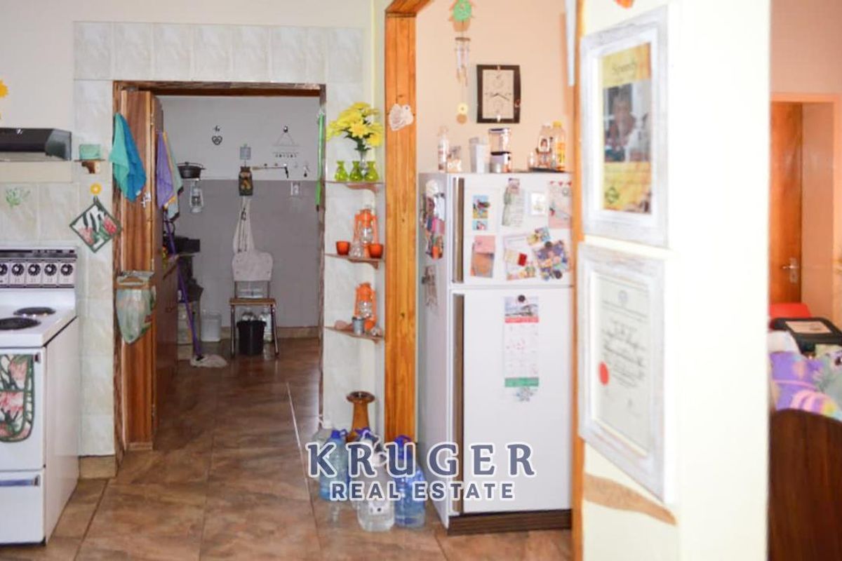 A functional kitchen area featuring a built-in stove and extractor fan, leading into a secondary scullery or utility space with tiled flooring.