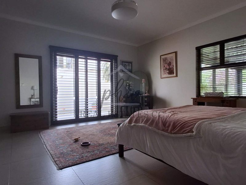 Spacious bedroom featuring tiled flooring, built-in cupboards, and sliding glass doors providing access to the exterior.