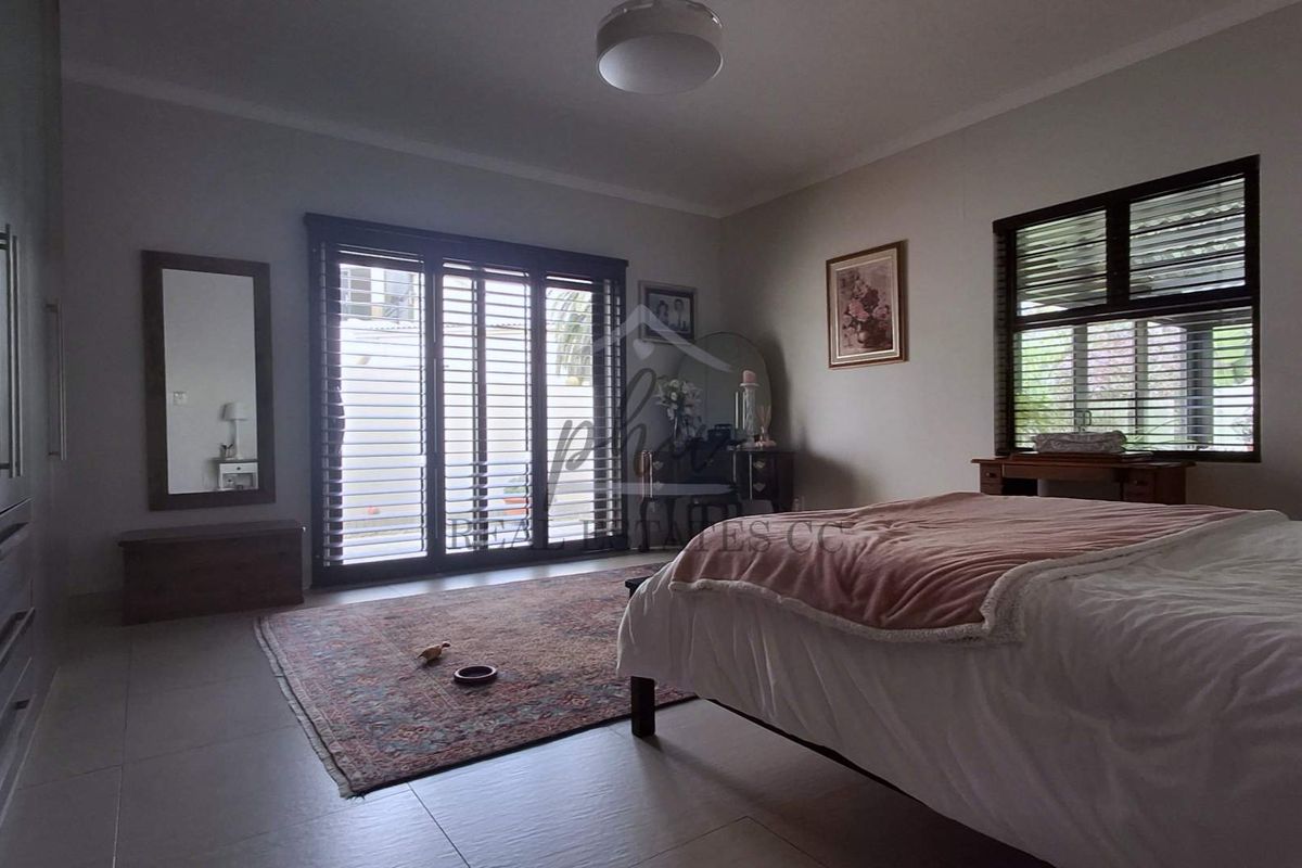 Spacious bedroom featuring tiled flooring, built-in cupboards, and sliding glass doors providing access to the exterior.