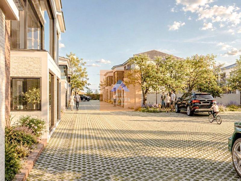 A modern townhouse development featuring a paved driveway, contemporary brick and glass facades, and landscaped surroundings in a residential estate setting.