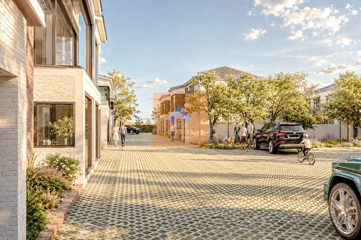 A modern townhouse development featuring a paved driveway, contemporary brick and glass facades, and landscaped surroundings in a residential estate setting.